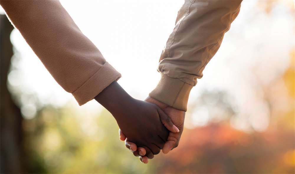 Una pareja que se da la mano mientras pasea al aire libre, una de las formas en que a las parejas con TDAH les resulta más fácil hablar cuando caminan uno al lado del otro